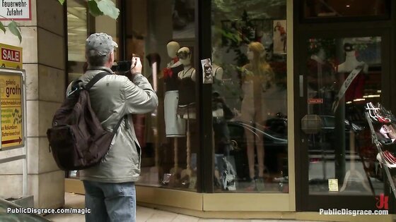 Slave posing naked in public window