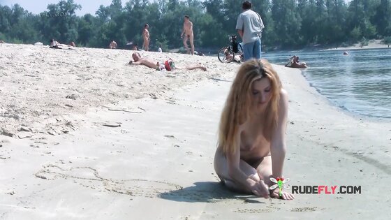 Playful blond nudist teen caught on camera naked at the beach