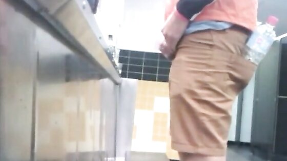 Guys in the urinals taking leak.