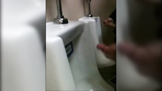 two slim dicks getting wanked at the urinals