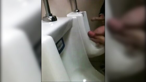 two slim dicks getting wanked at the urinals